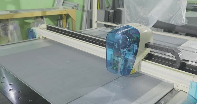 CNC Fabric Cutting Process in Modern Manufacturing Workshop. Automated Textile Cutting on CNC Plotter Machine. Digital cutting system (automatic cutting plotter) in operation. 