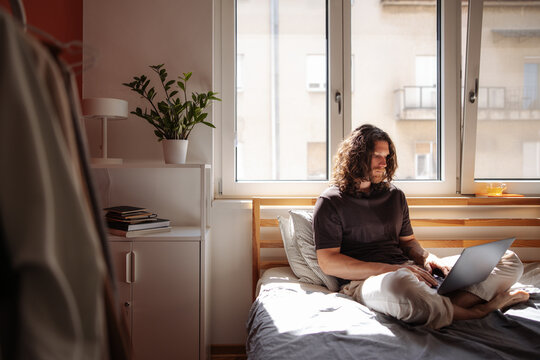 Man Working Remotely on Laptop in Bedroom
