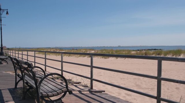 Coney Island beach promenade in Brooklyn, New York, United States. Wooden boardwalk near retro luna park. Benches on ocean coast, sandy beach. Waterfront summer holiday in NYC, USA. Outdoor recreation