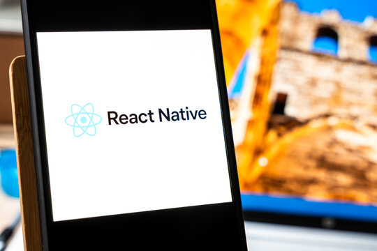 Warsaw, Poland - July 6, 2026: Close-up of smartphone displaying React Native logo, showcasing mobile app development technology in a modern office environment.