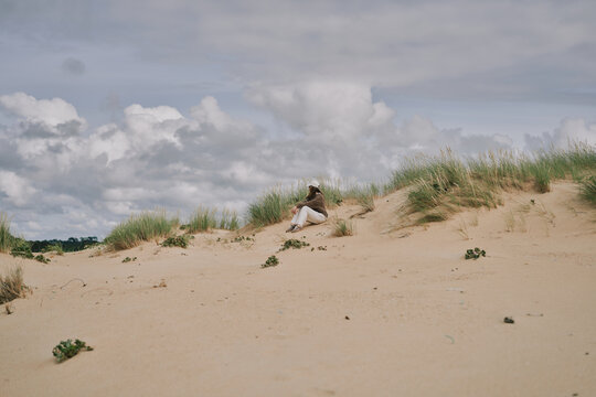 Woman Standing on Windy Sand Dunes at the Beach Wearing Casual Outfit