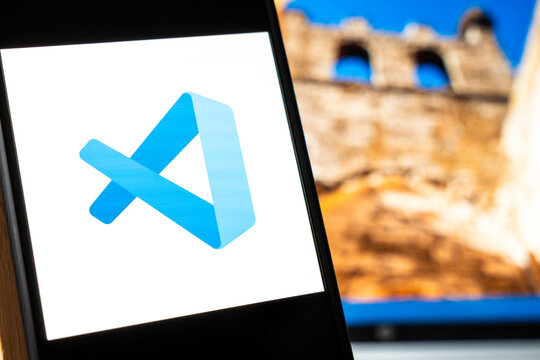 Warsaw, Poland - July 6, 2026: Visual Studio Code logo displayed on smartphone screen with blurred historic building in background, demonstrating use of technology in software development