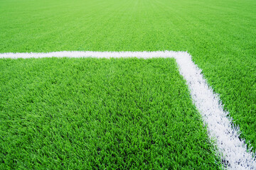 Football field corner marking artificial turf soccer field white line creating clean sports background with vivid green synthetic grass © AlienCat