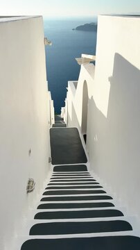 White architecture in Santorini island, Greece. Steps to the sea. Blue sea and the blue sky at sunset. Travel and summer vacation concept. Vertical video
