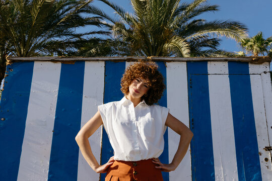 Woman posing against striped beach hut
