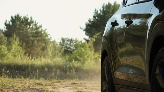 black crossover car drives past the camera in nature. close-up, bottom view