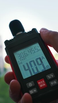 A person hand holds a professional sound level meter displaying 40.9 decibels against a bright background. The digital screen also shows humidity and temperature readings in real time.