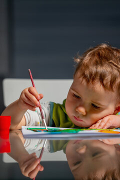 Focused toddler painting with a brush during a creative learning activity at home.