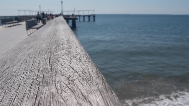 Coney Island beach, wooden pier promenade in Brooklyn, New York, United States. Boardwalk near retro luna park. Ocean coast sandy beach. Defocused people on waterfront summer holiday in NYC, USA.