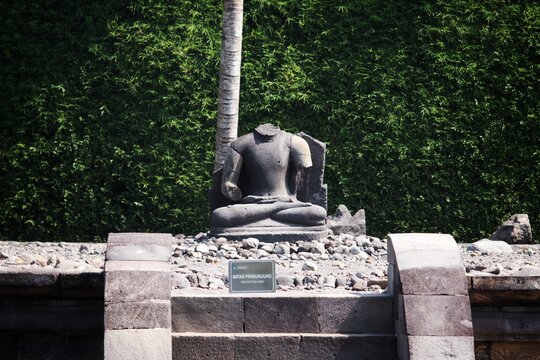 Ancient headless stone Buddha statue sitting in a meditative pose on an open altar at Candi Ngawen temple, Muntilan, Central Java, Indonesia.