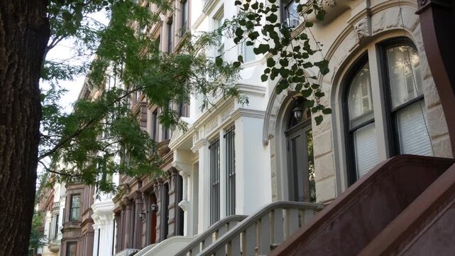 New York City townhouse buildings, brownstone row houses in Manhattan or Brooklyn, United States of America. Classic buildings on residential district street. Real estate property. Rowhouse townhome.