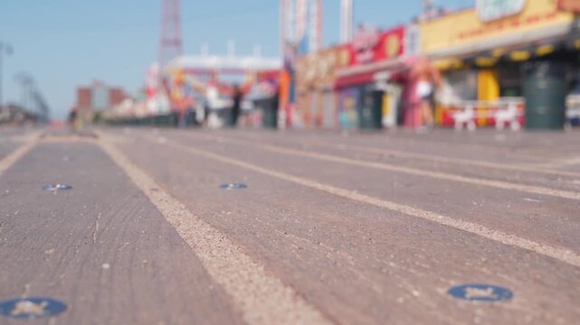 Coney Island beach promenade in Brooklyn, New York, United States. Wooden boardwalk near retro luna park. Amusement park on ocean coast beach. Waterfront summer holiday, people walking on promenade.