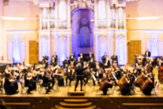 Blurred background of a symphony orchestra with conductor performing on stage in a concert hall