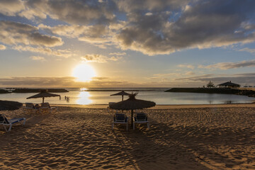 Fototapeta premium Tropical Beach Resort at Sunset with Empty Sunbeds under Straw Umbrellas