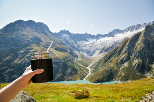 Hand holding a thermal food flask in the mountains