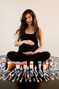Pregnant woman surrounded by fertility needles and syringes