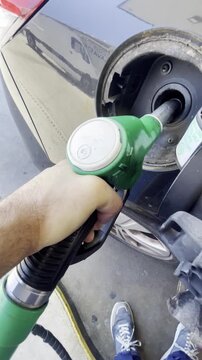 Gasolinera y manguera de surtidor de coche con cliente echando gasolina llenar dep&oacute;sito repostar combustible OPEP en estaci&oacute;n de servicio low cost