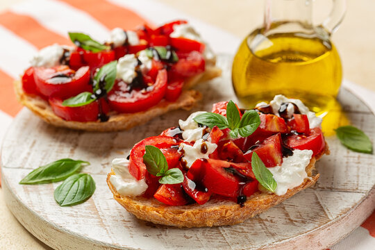 Bruschetta with creamy burrata cheese, fresh tomatoes, balsamic vinegar glaze and basil leaves. Italian summer appetizer. Olive oil bottle.