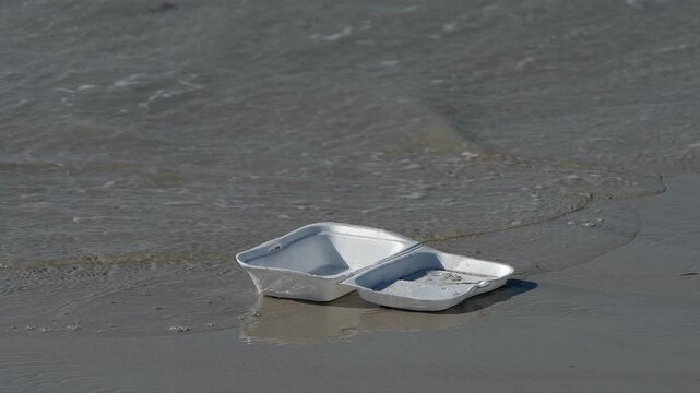 person picking up plastic litter from ocean beach