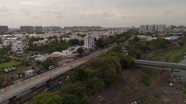 Aerial Drone View of Surat Flyover Bridge with Urban Skyline, Residential Neighborhoods, Green Trees and Transportation Infrastructure in Gujarat India