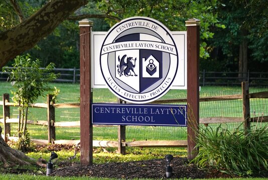 New Castle County, Delaware, U.S.A - Jul 1, 2026 - Centreville Layton School sign with emblem, motto, wooden posts, grassy area, trees, and fence.