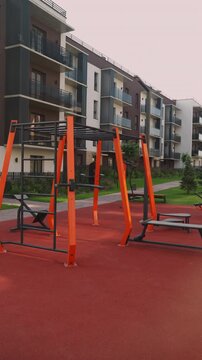 Empty modern outdoor gym with exercise equipment and rubber flooring. A public calisthenics park in a residential courtyard for fitness