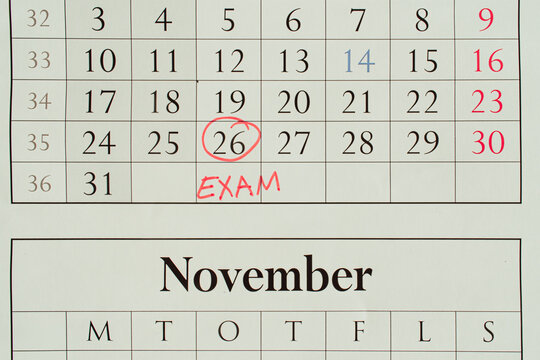 Exam date marked with a red circle on a wall calendar, student planning concept