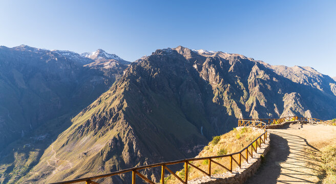 A curved stone pathway with wooden railings lines the Mirador de Tapay viewpoint in Peru, offering panoramic views of the Colca Canyon and Surihuiri peak