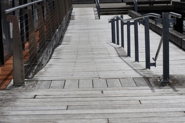 Fototapeta premium weathered wooden ramp, aged wooden planks forming sloping pedestrian route, metal handrail (landscape, safety, accessible) 4723