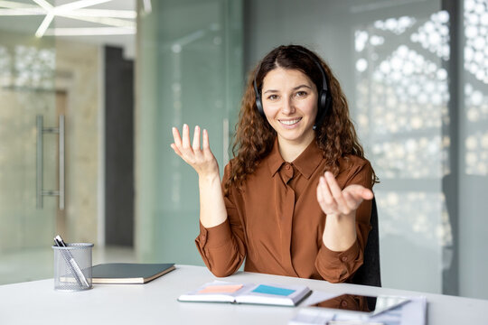 Young female call center agent wearing headset and smiling while providing effective customer support and helping clients in a modern office environment
