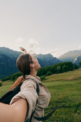 Naklejka premium Cheerful woman outdoors, arms raised, enjoying mountain scenery, backpack ready, sunlit moment, fresh breeze, natural colors, expansive valley background