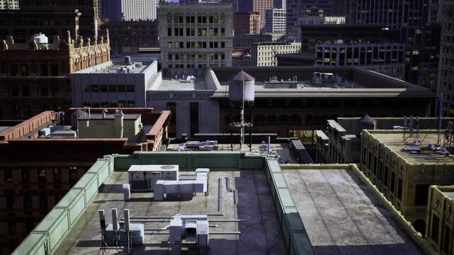 Roof mechanical units overlooking urban blocks weathered flat roof with vents, ducts, condenser boxes and parapet, textured gravel and tar, low angled light