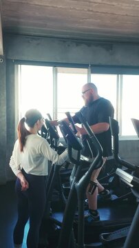 Focused woman using a chest press machine at the gym, performing strength training with controlled form amid weight equipment.