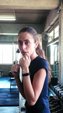 Focused woman throwing a straight punch in a gym, practicing boxing form among weight machines and natural light.