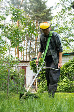 Man trimming grass in a backyard garden