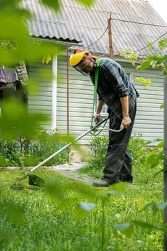 Man trimming grass in a backyard during springtime