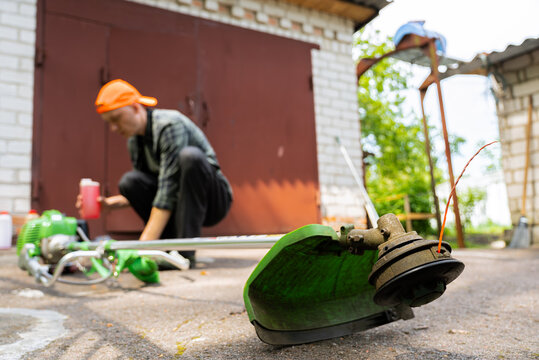 Man preparing grass trimmer in rural backyard