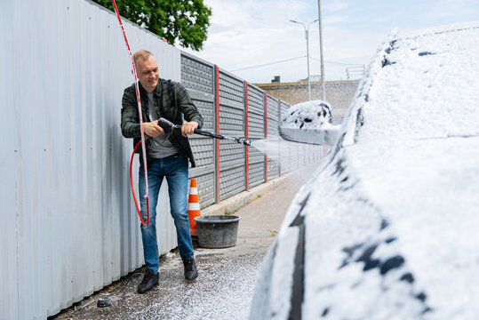 Man washing car with foam at self service car wash bay