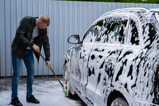 Man washing a soapy car at self service car wash bay