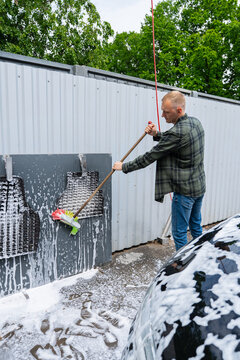 Man washing car mats at self-service carwash station