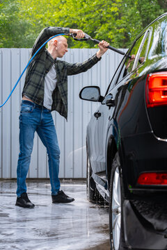 Man washing SUV at self service car wash with pressure hose