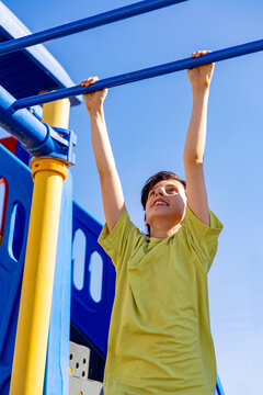 Boy hanging from monkey bars at outdoor playground