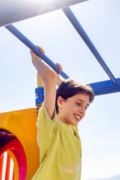 Boy hanging from monkey bars on sunny outdoor playground
