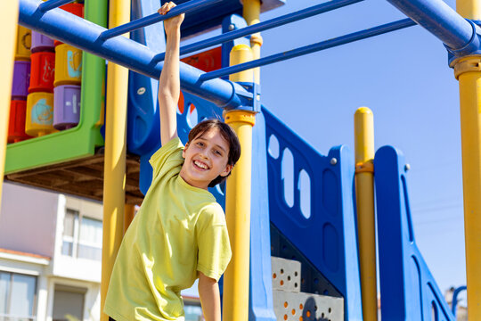 Smiling boy hanging from monkey bars at outdoor playground