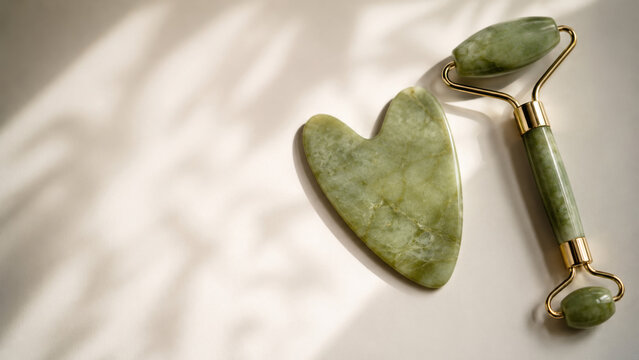 Green Jade Gua Sha and Facial Roller With Golden Hardware in Sunlight