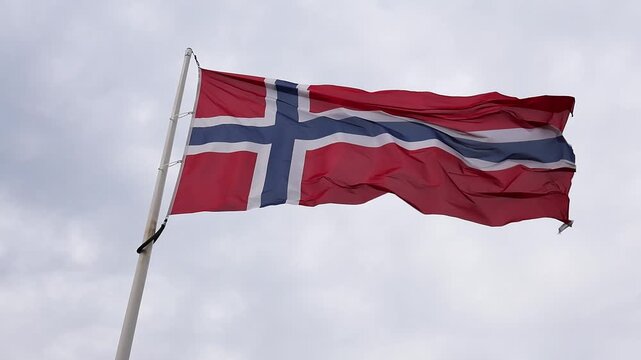 Norwegian flag waving in slow motion in the wind against a cloudy sky
