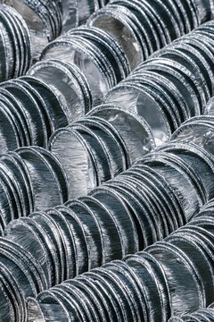 Stacks of round aluminum containers for food packaging. Metallic pans for baking and cooking. Raw material for recycling and industrial metal waste management concept.