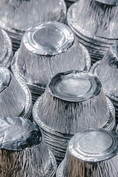 Stack of empty aluminum foil containers for food. Metallic circular trays for recycling and waste management. Sustainable packaging material, ecology and environmental protection concept.