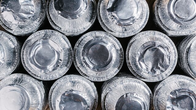 Stack of round aluminum foil containers viewed from above. Metal trays for food storage and packaging. Concept of sustainable waste management and recycling of reusable kitchen materials.