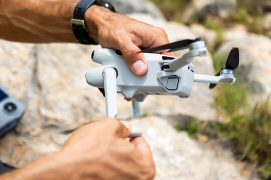 Hand preparing compact drone for outdoor flight on rocky ground